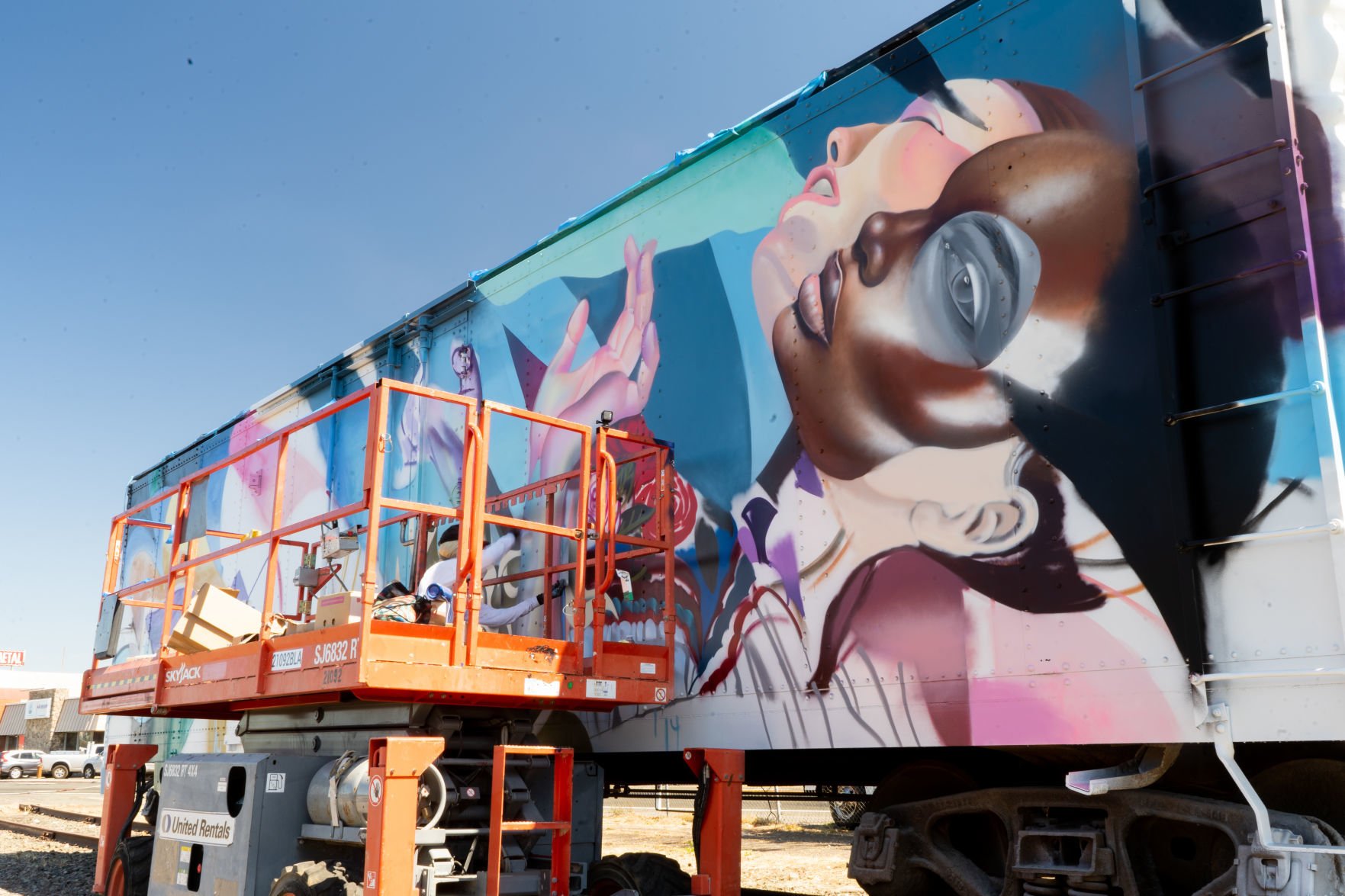 ELLE, a graffiti/street artist/muralist, works on a rail car art installation near the Wine Train car barn.